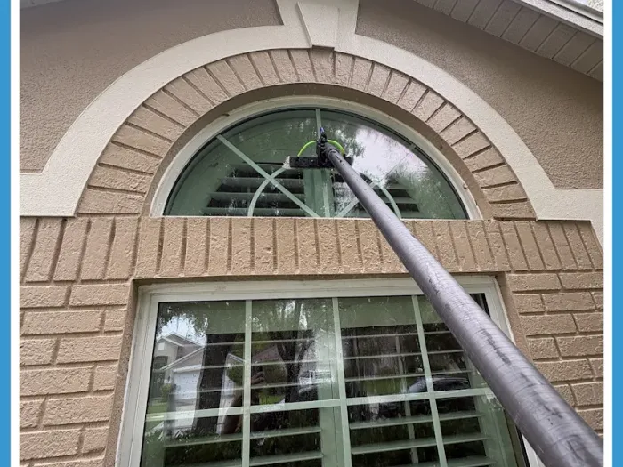 Water-fed pole cleaning an arched second-story window on a brick Tampa home