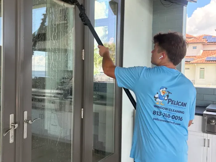 Cleaning french doors beside the outdoor kitchen at a waterfront Tampa home