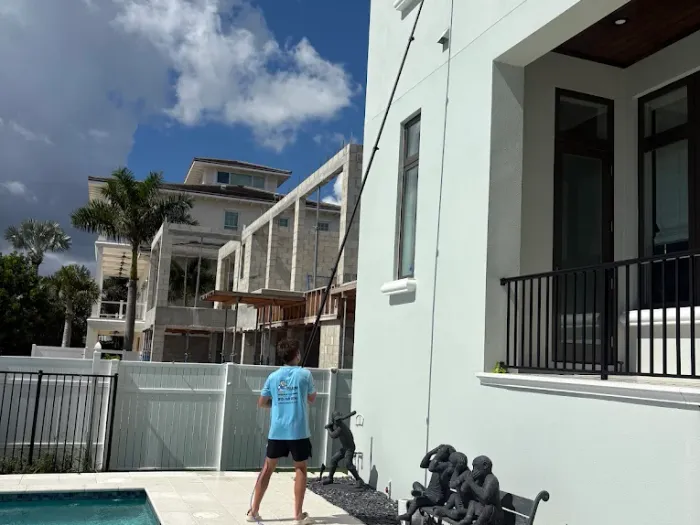 Cleaning upper-story windows above the pool at a waterfront Tampa estate