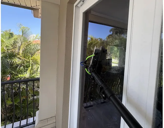 Cleaning a sliding glass door from a second-floor balcony in Tampa