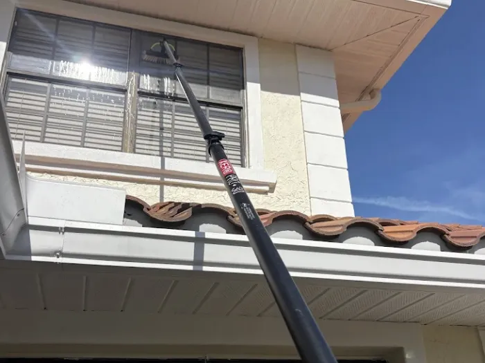 Water-fed pole cleaning second-story windows on a tile-roof Tampa home