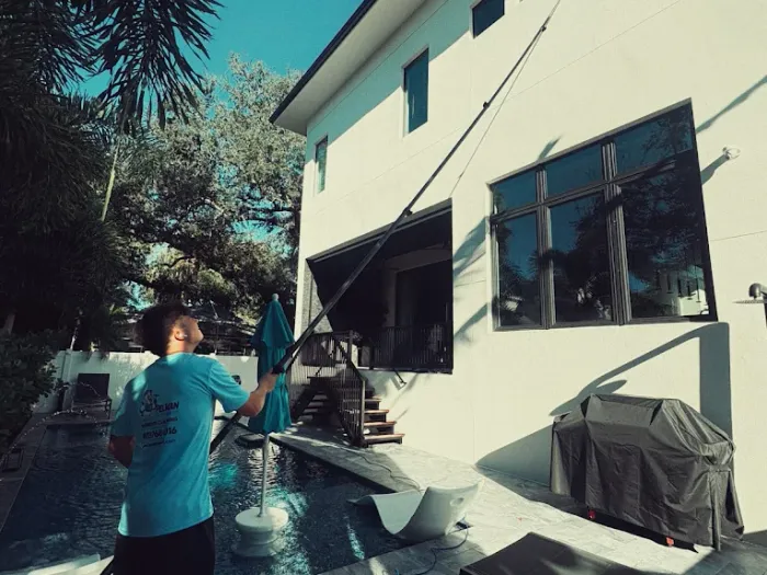 Pelican Exteriors technician cleaning poolside glass at a modern Tampa home
