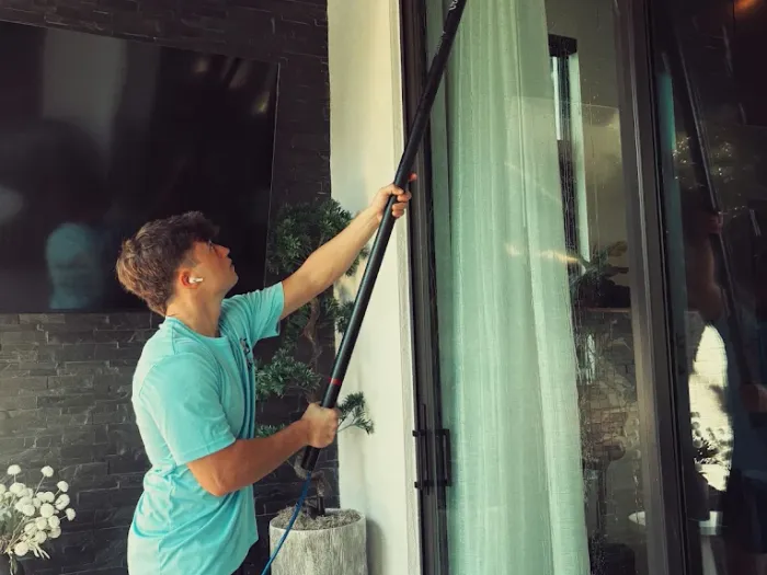 Pelican Exteriors technician cleaning tall entry glass at a Tampa home